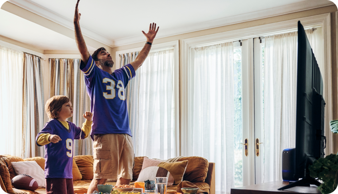 Father and son cheering while watching TV