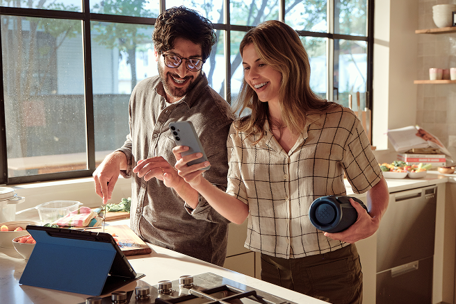 Man and woman connecting a smartphone to a speaker