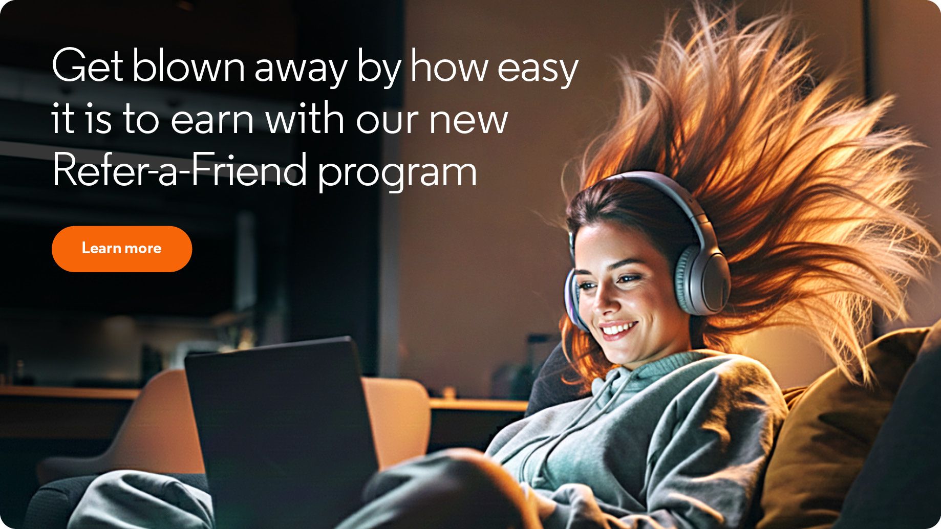 a woman on a couch wearing headphones and using a laptop computer with her hair blowing backwards