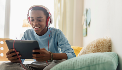 A teen games on his tablet enjoying lag-free Optimum Internet.